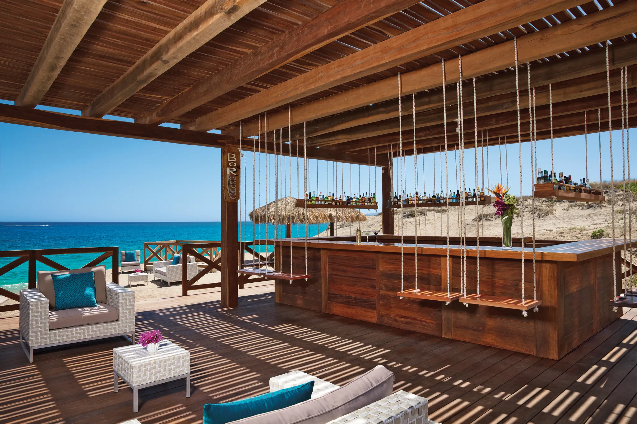 Barracuda Beach Bar at Secrets Puerto Los Cabos featuring oceanfront seating, tropical cocktails, and relaxed beachfront ambiance.