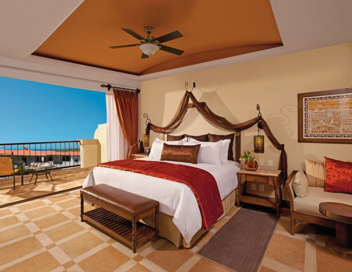 Junior Suite Garden View with king bed and private balcony at Secrets Puerto Los Cabos Golf & Spa Resort overlooking lush grounds.