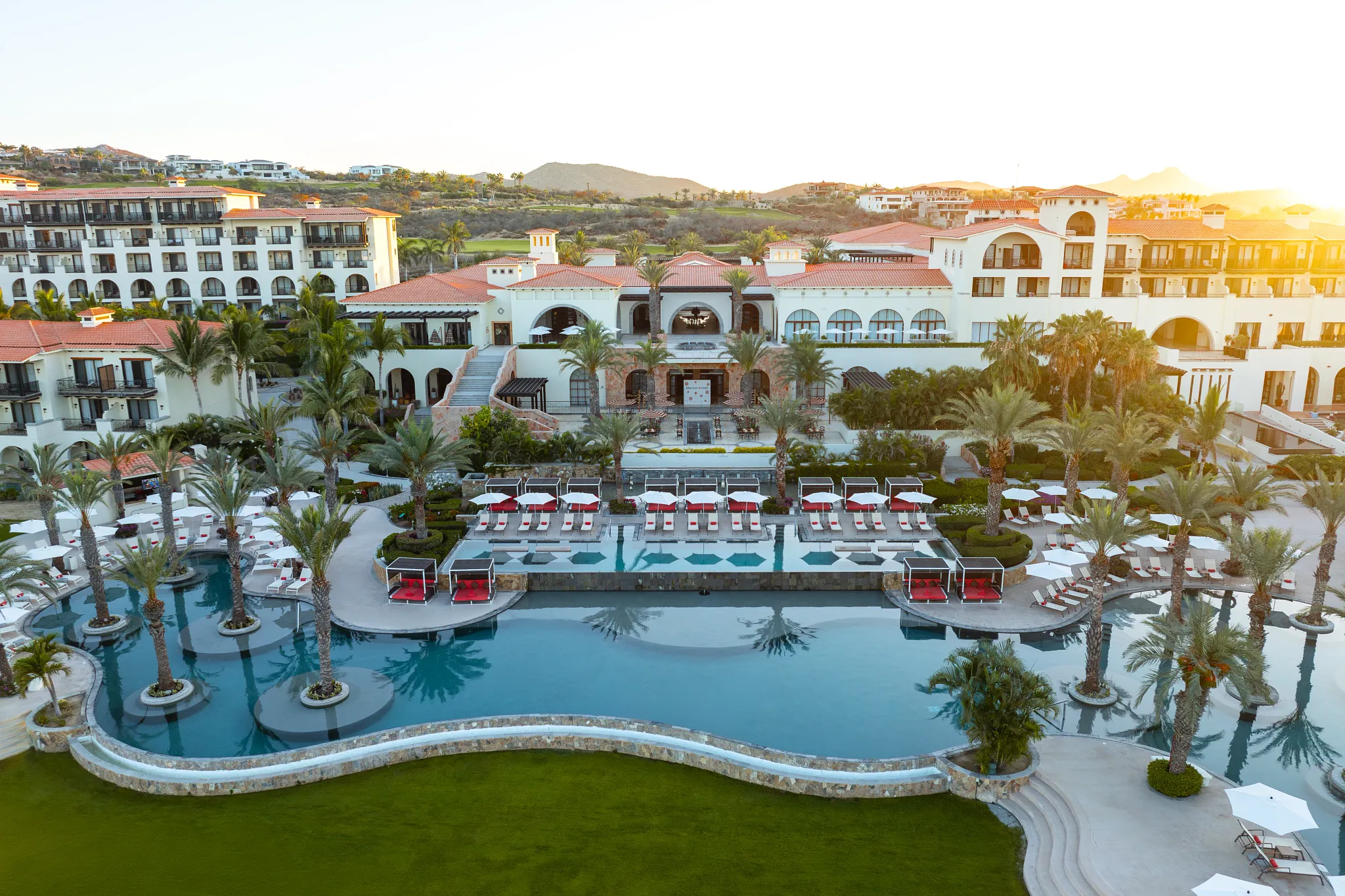 Expansive main pool and resort buildings at Secrets Puerto Los Cabos with ocean views in Cabo San Lucas.
