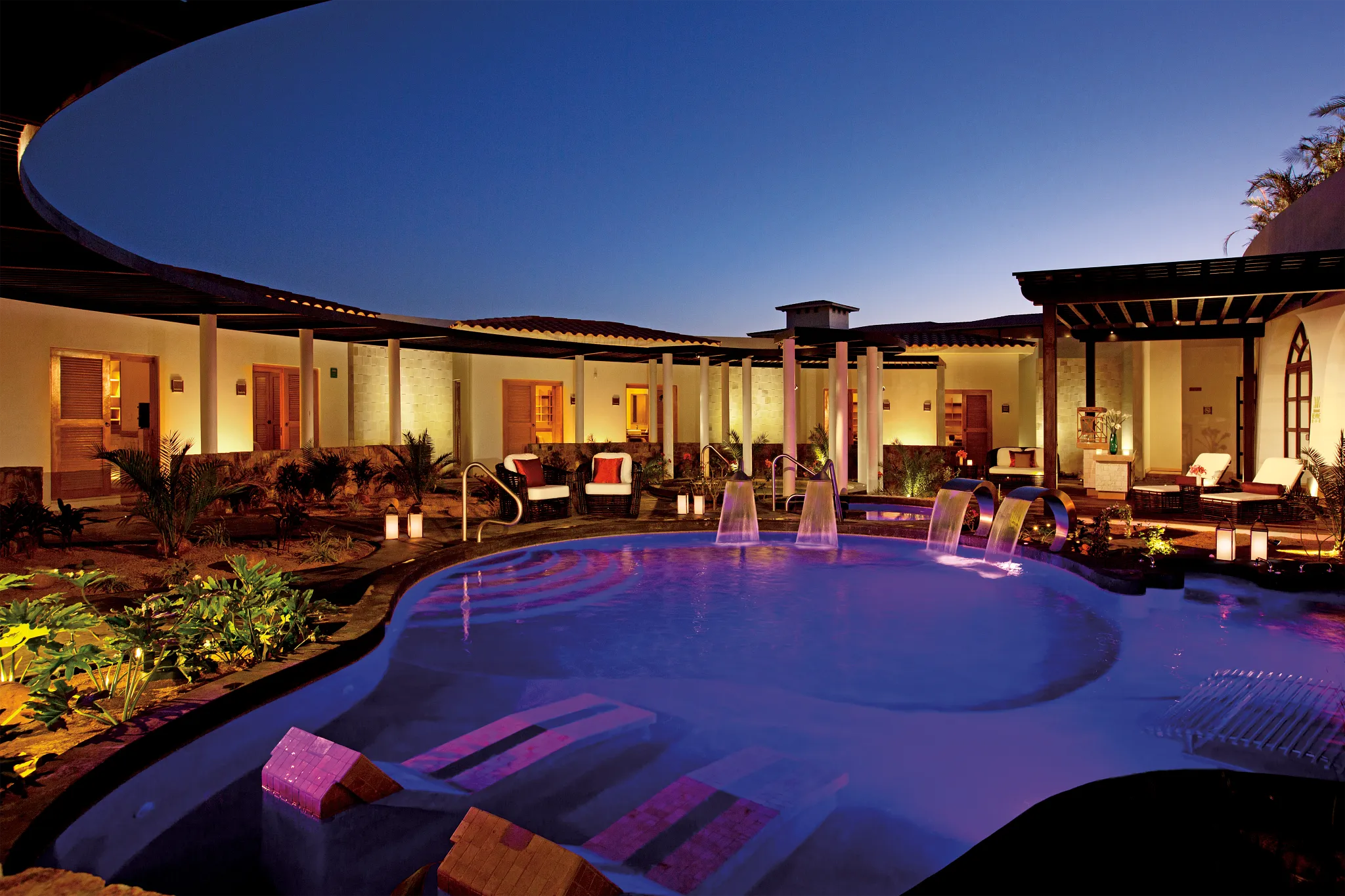 Illuminated spa pool with water features at night at Secrets Puerto Los Cabos resort.
