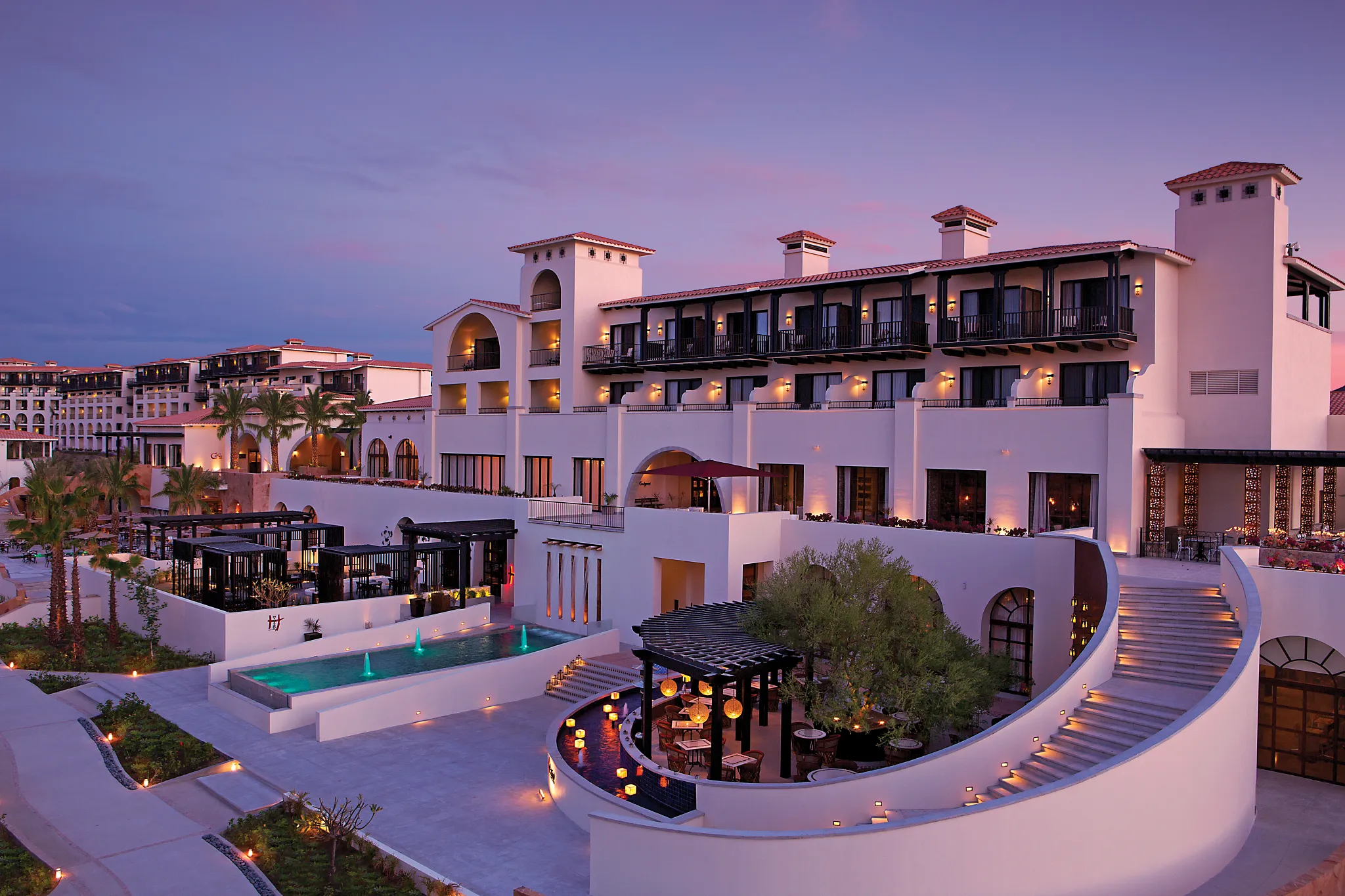 Resort main building illuminated at sunset at Secrets Puerto Los Cabos Golf & Spa Resort.